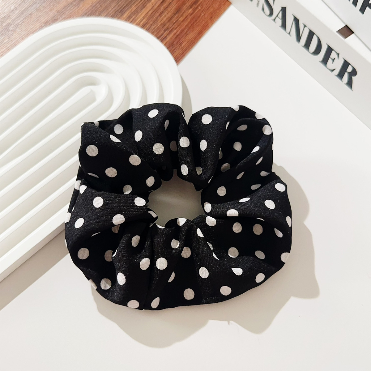Svart retro hårsnodd i tyg med vita prickar inspirerad av 1950-talets klassiska polka dot-mönster.